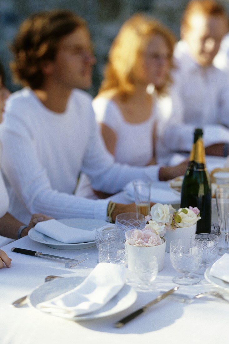 Friends sitting at table laid for special occasion with champagne