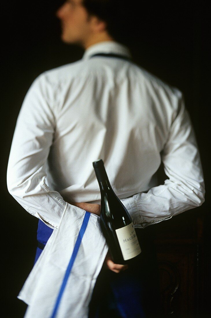 Sommelier with a bottle of wine behind his back