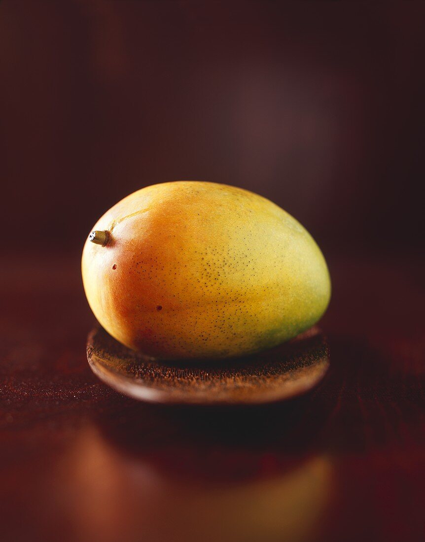 Eine Mango auf einem Holzteller