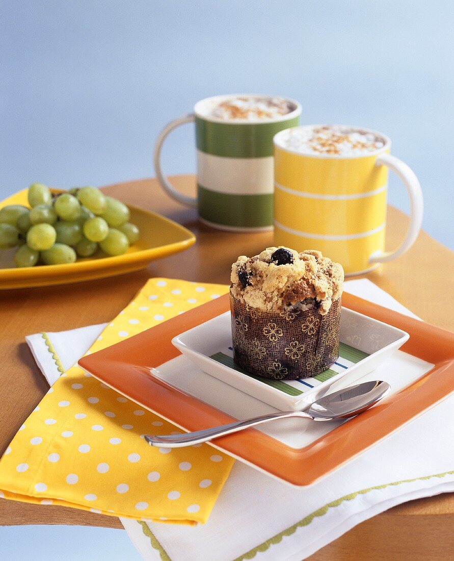 Blueberry muffin with two cups of cappuccino