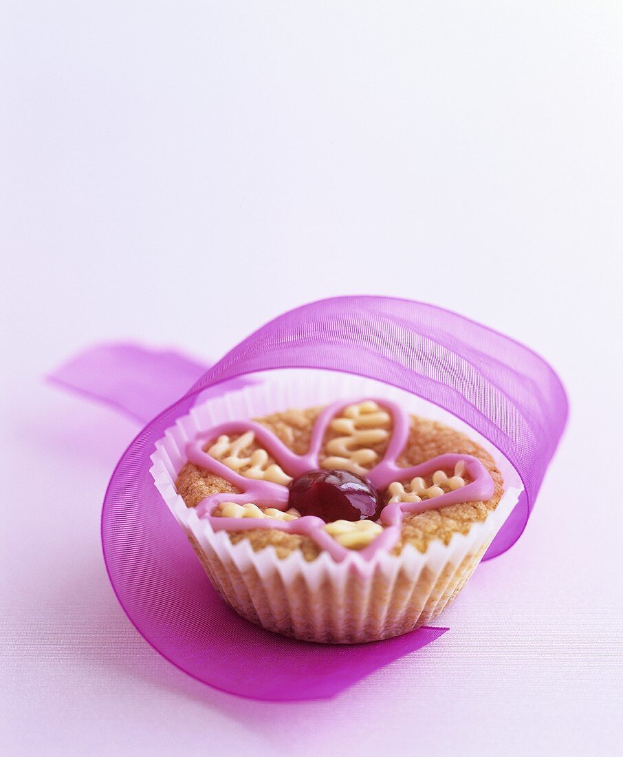 Muffin mit Blumen-Zuckerguss und Geschenkband