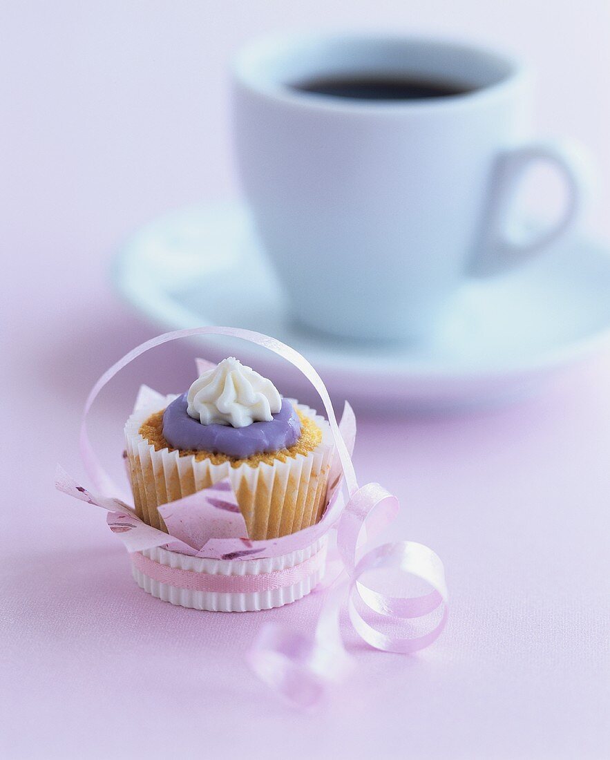Muffin mit bunter Zuckerglasur mit einer Tasse Kaffee