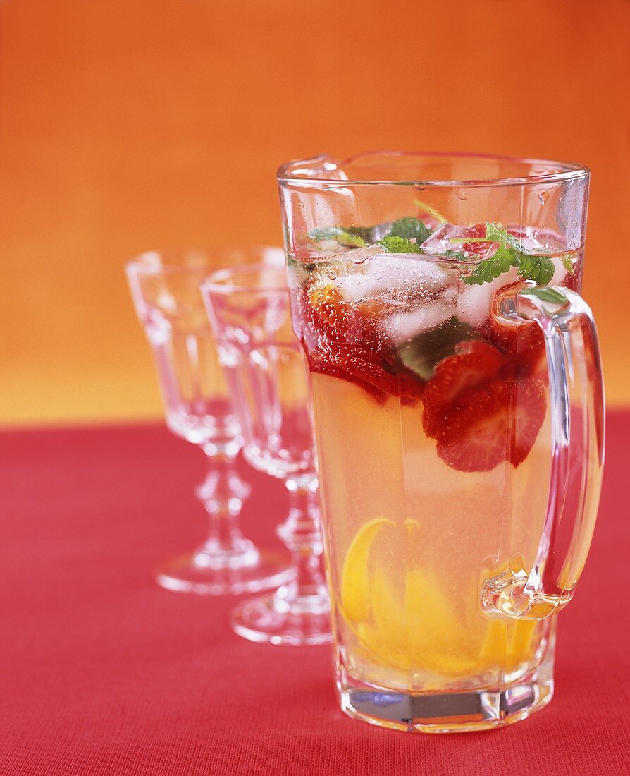 Lemonade with strawberries and mint in jug, two glasses