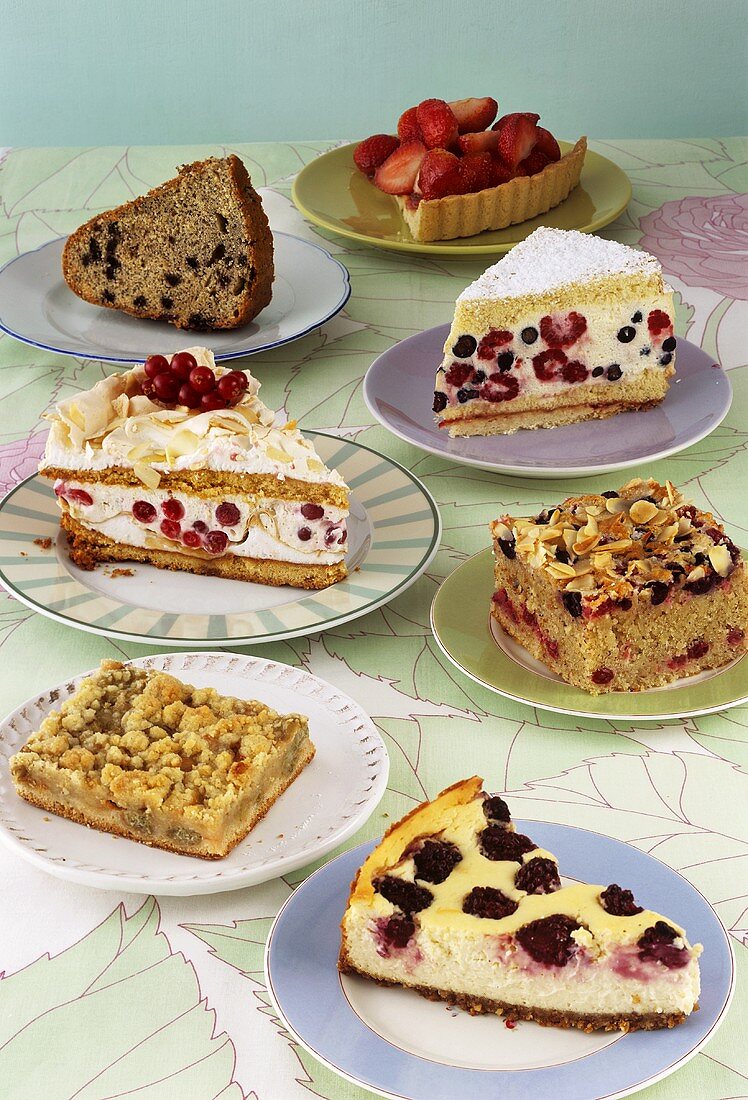 Seven different pieces of cake made with berries