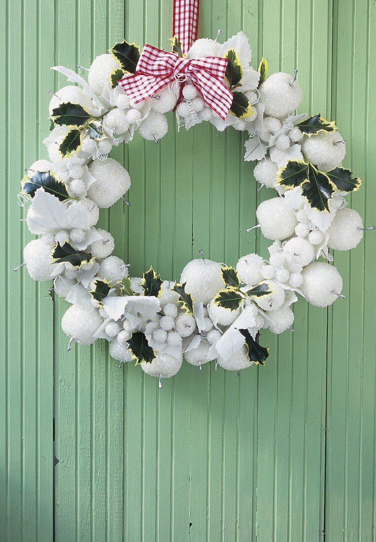 White Christmas wreath hanging on turquoise wooden wall