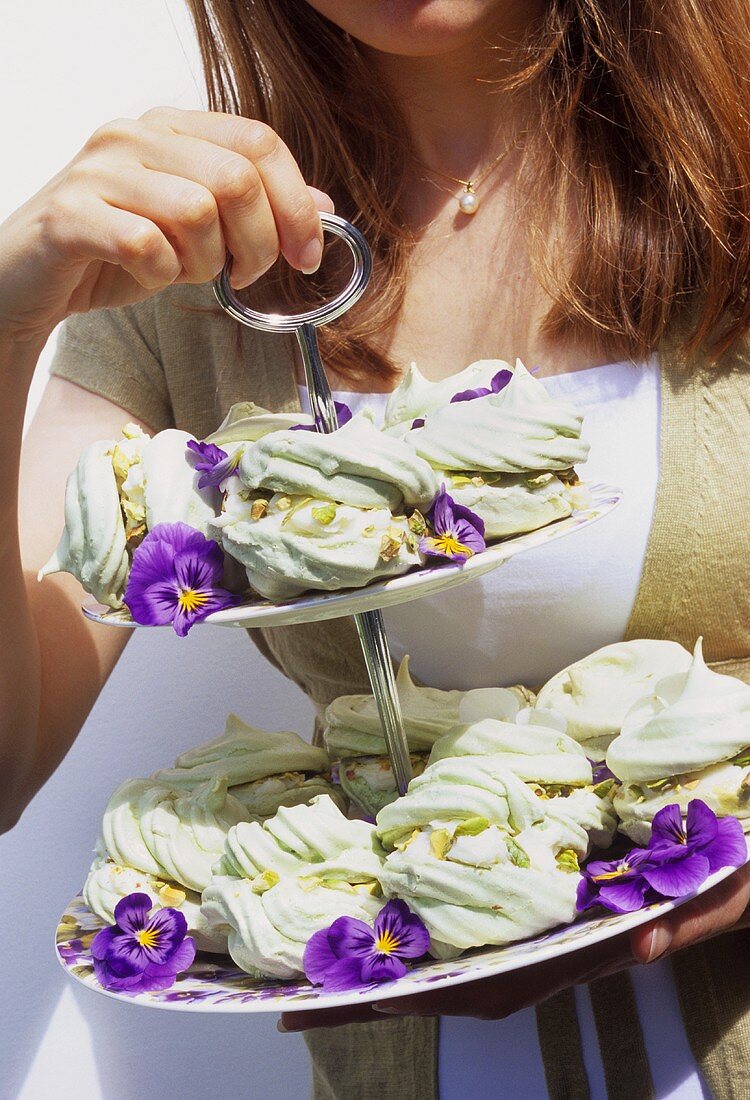 Young woman carrying pistachio meringues on tiered stand