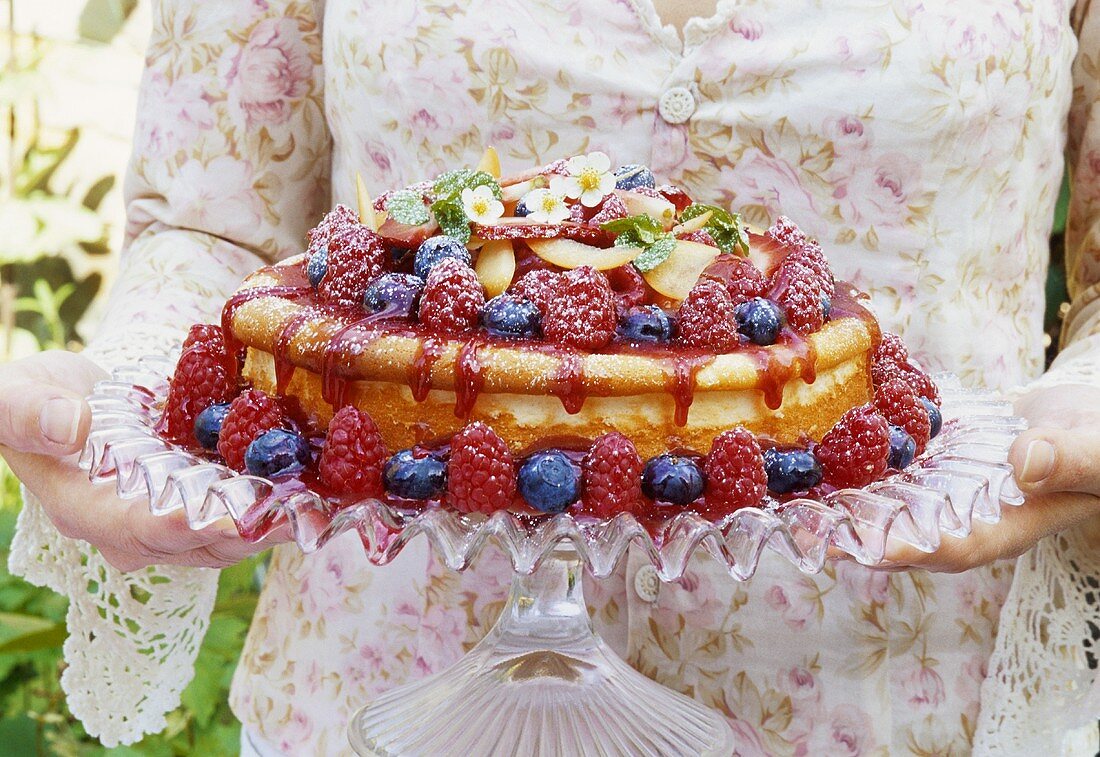 Junge Frau hält Käsekuchen mit frischen Beeren