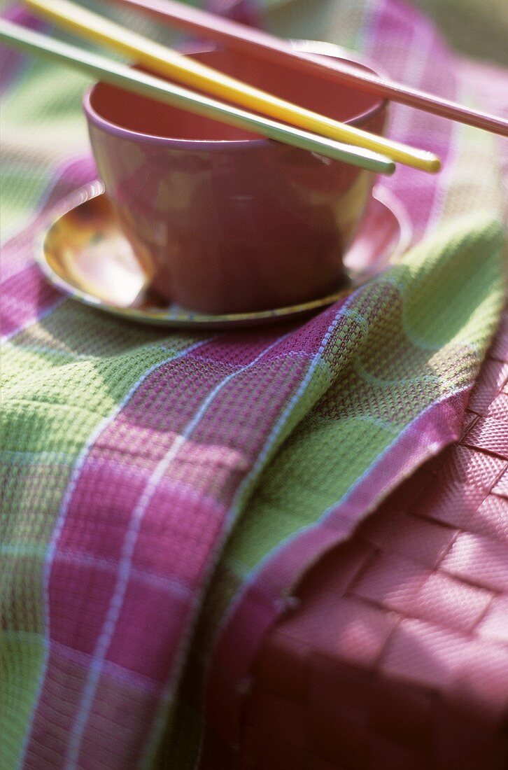Bowl with chopsticks on coloured tea towel