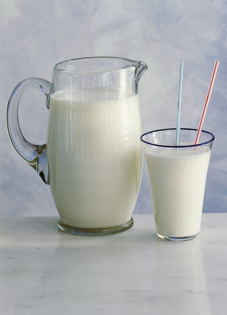 Milchkrug mit einem Glas und Trinkhalmen