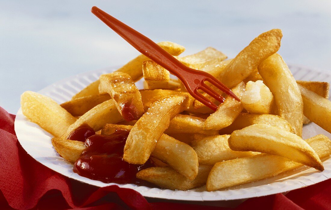 Chips with red plastic fork and ketchup on paper plate