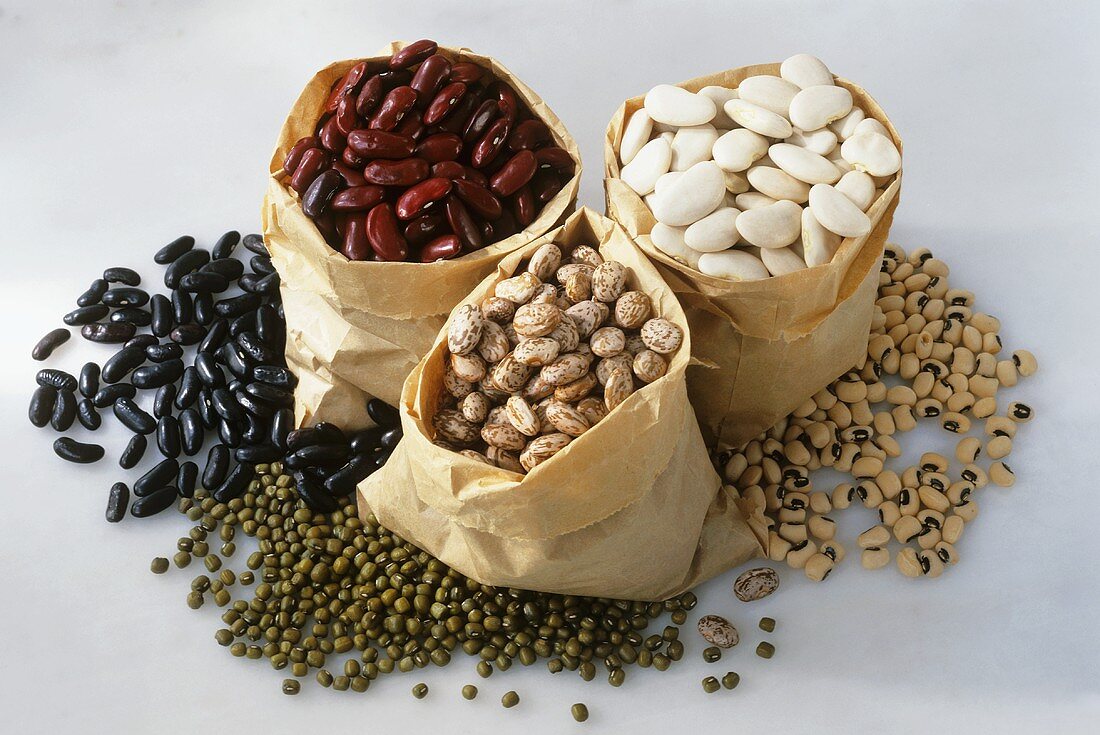 Various types of beans in and beside paper bags