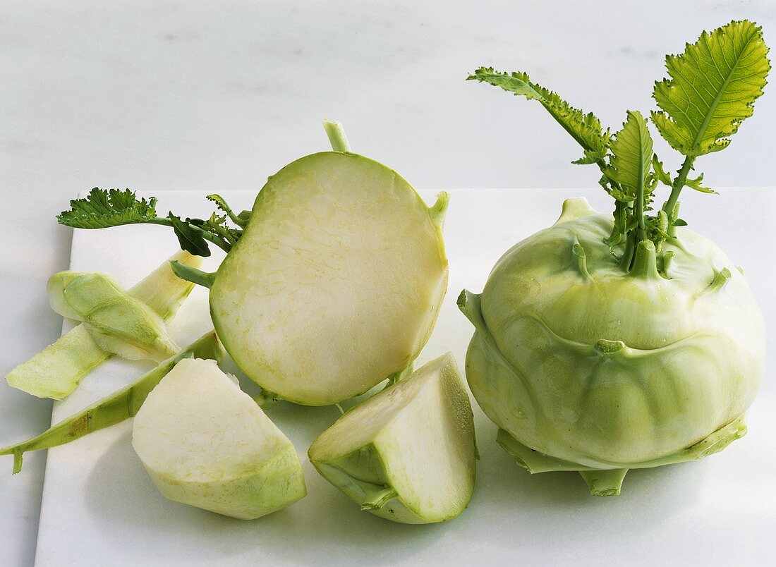 Ganzer und geschnittener Kohlrabi auf einem Schneidebrett