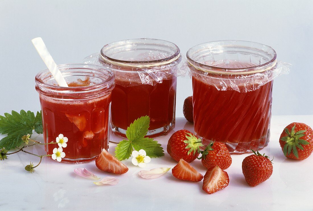 Three jars of strawberry jelly with rose petals