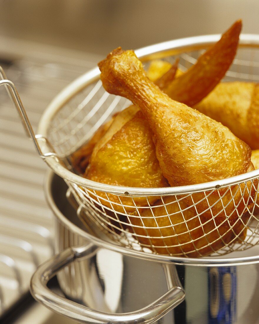 Deep-fried chicken drumsticks in a deep-frying basket
