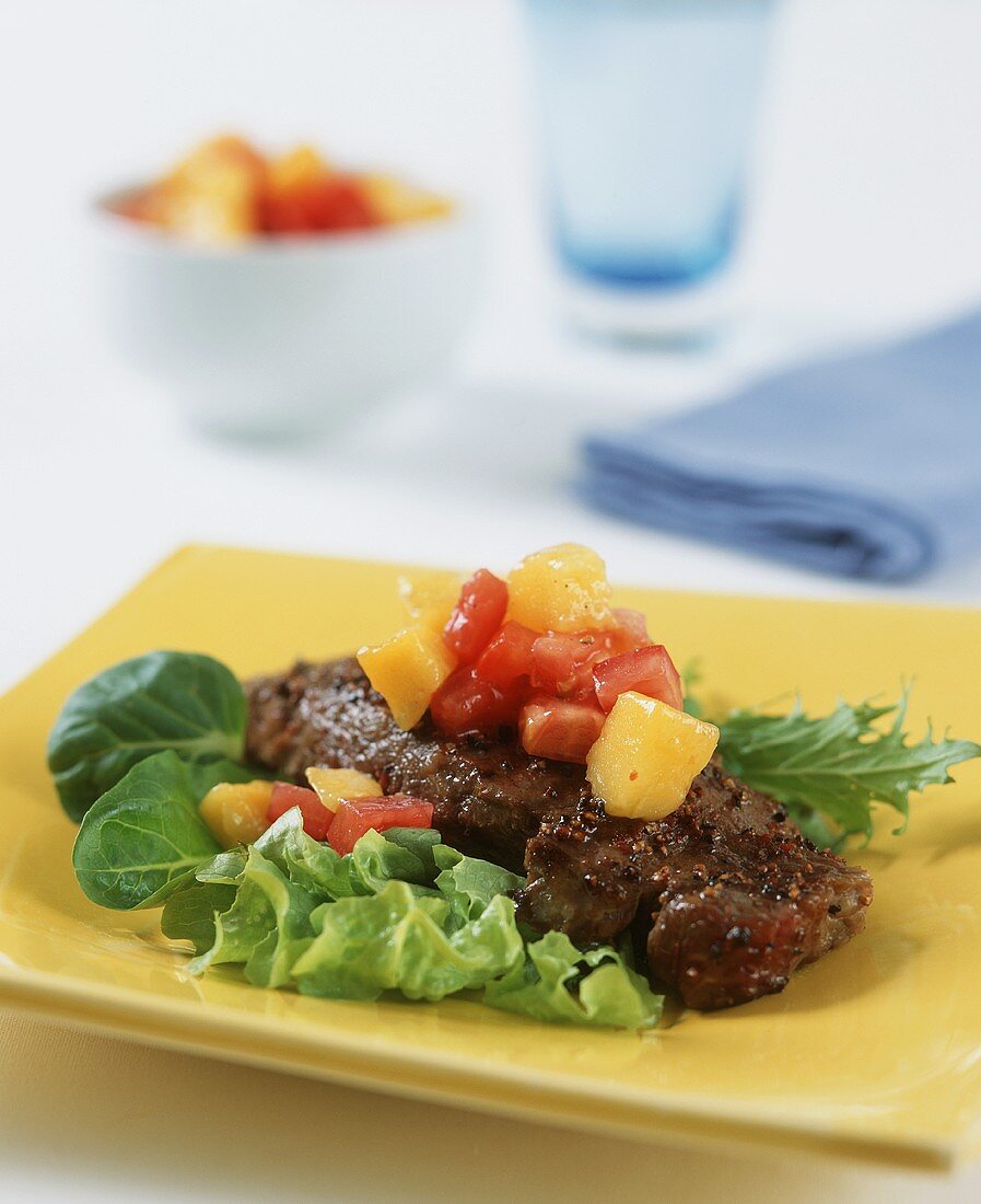 Beefsteak with mango and tomato salsa on salad leaves