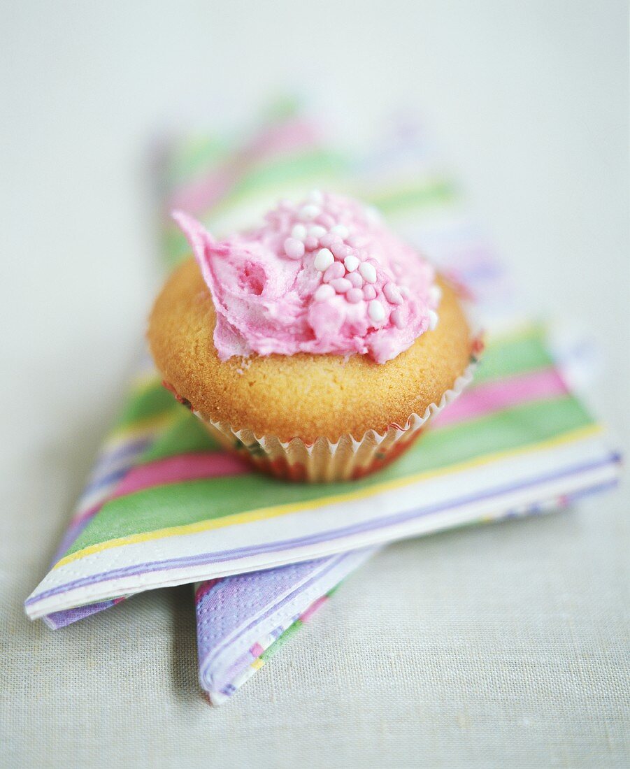 Cupcake mit rosa Zuckercreme und Zuckerperlen