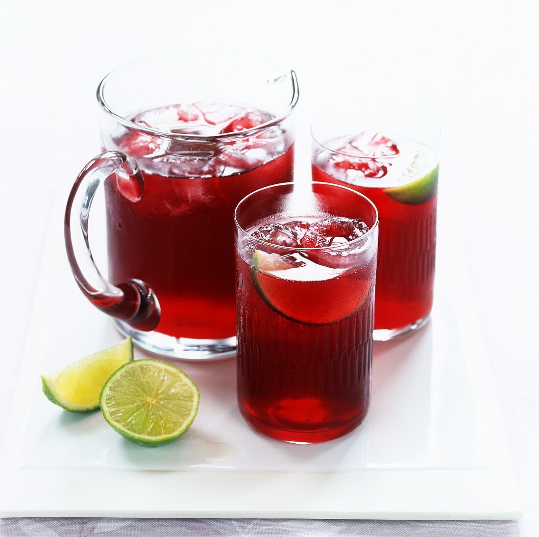 Cranberry juice with ice and lime in jug and two glasses