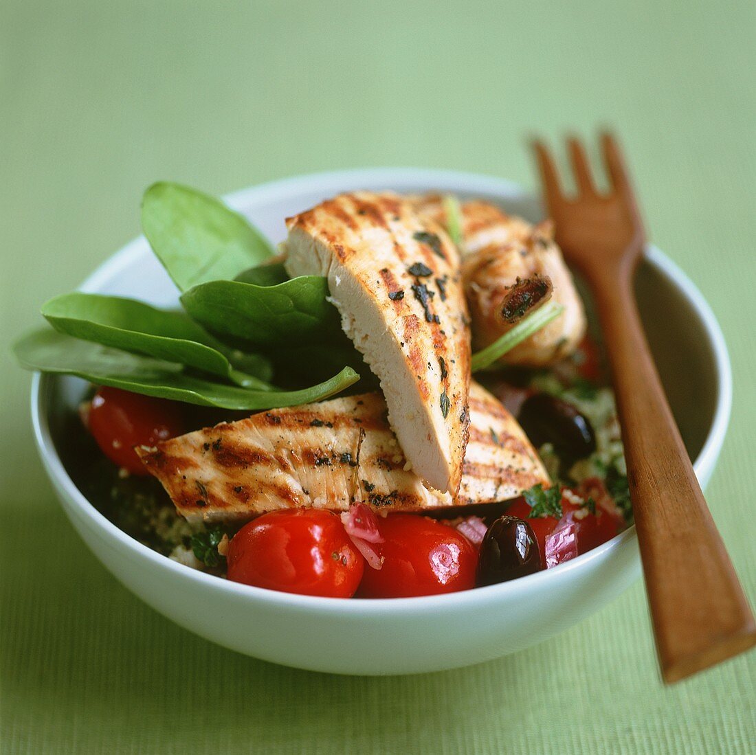 Barbecued chicken breast on couscous with tomatoes and olives