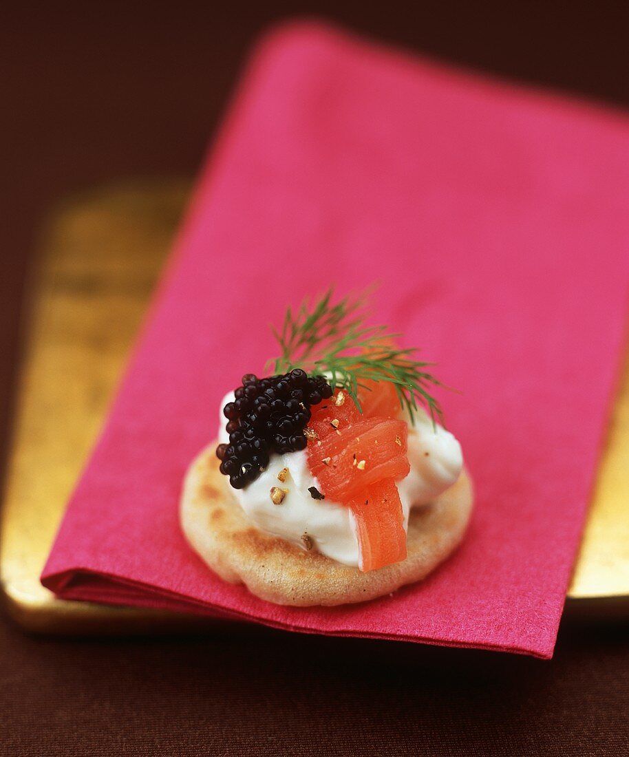 Small blini topped with creamed horseradish, smoked salmon and caviar