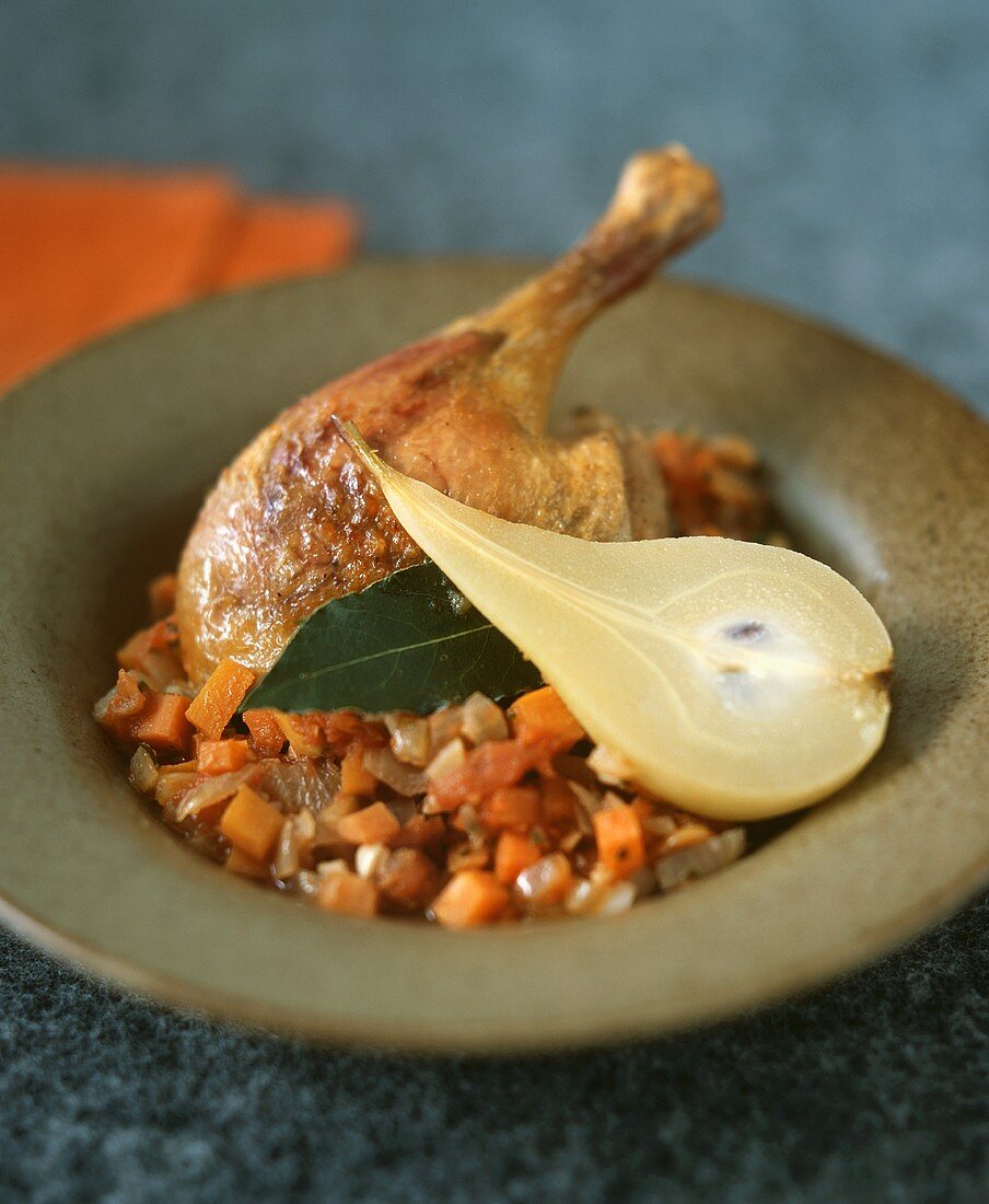 Duck leg on a bed of vegetables with pear