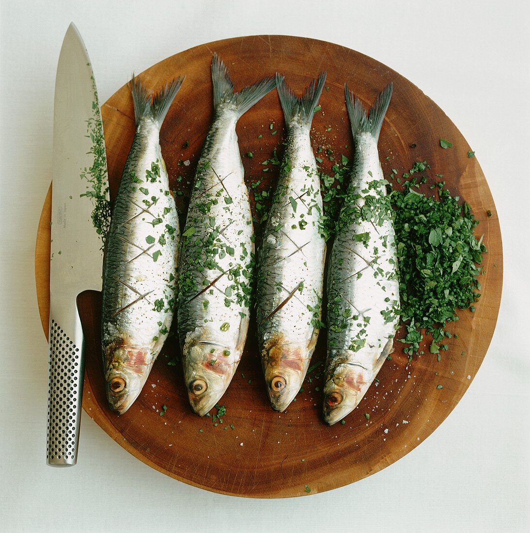 Sardines with parsley on a chopping board