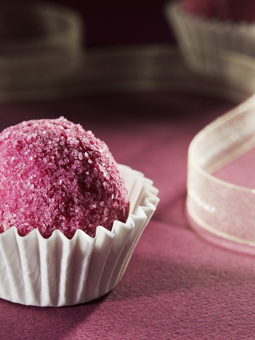 Praline mit rosafarbenem Zucker in einem Pralinenförmchen