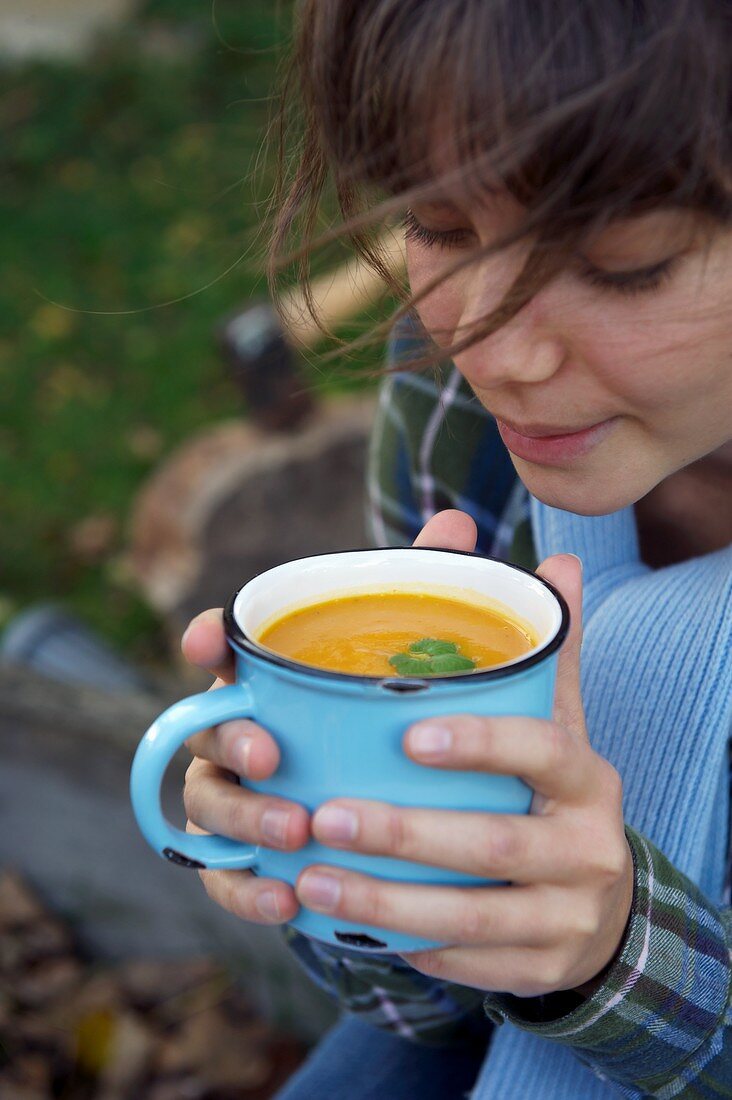 Mädchen mit Kürbiscremesuppe in der Tasse