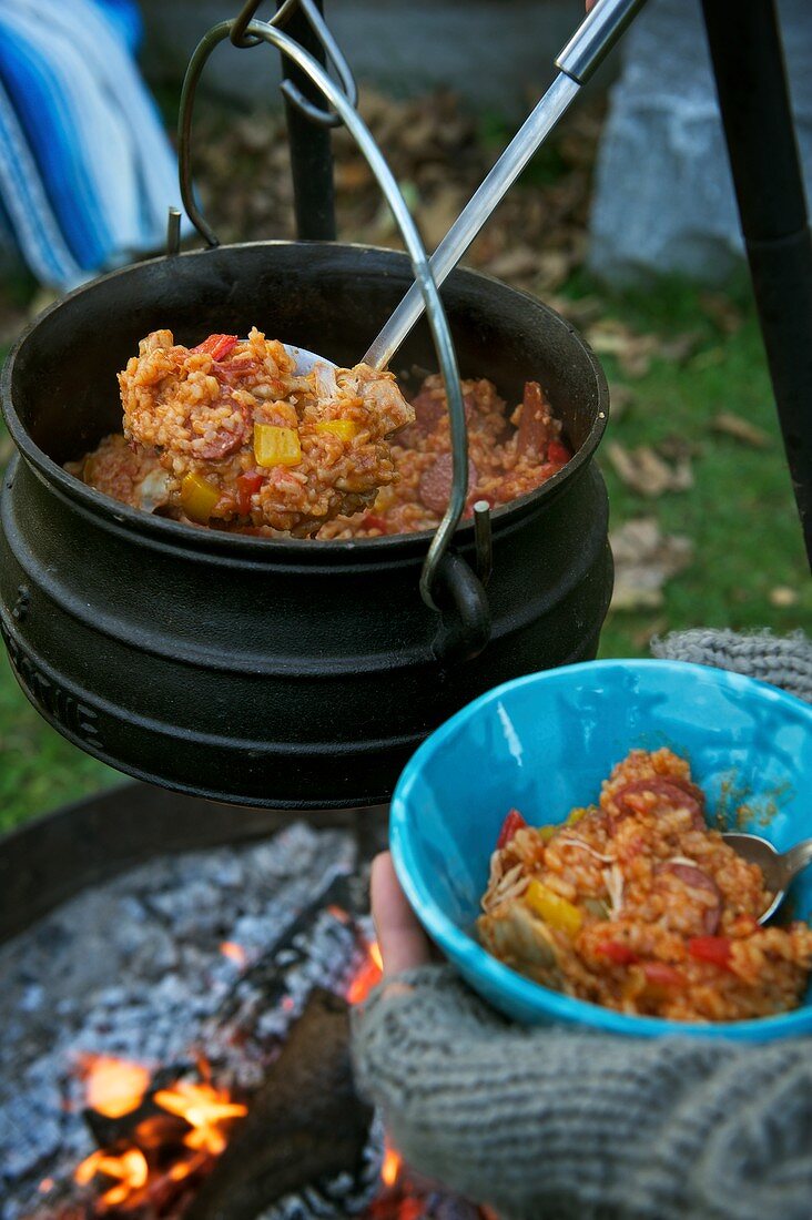 Rice stew with chicken and sausages being served