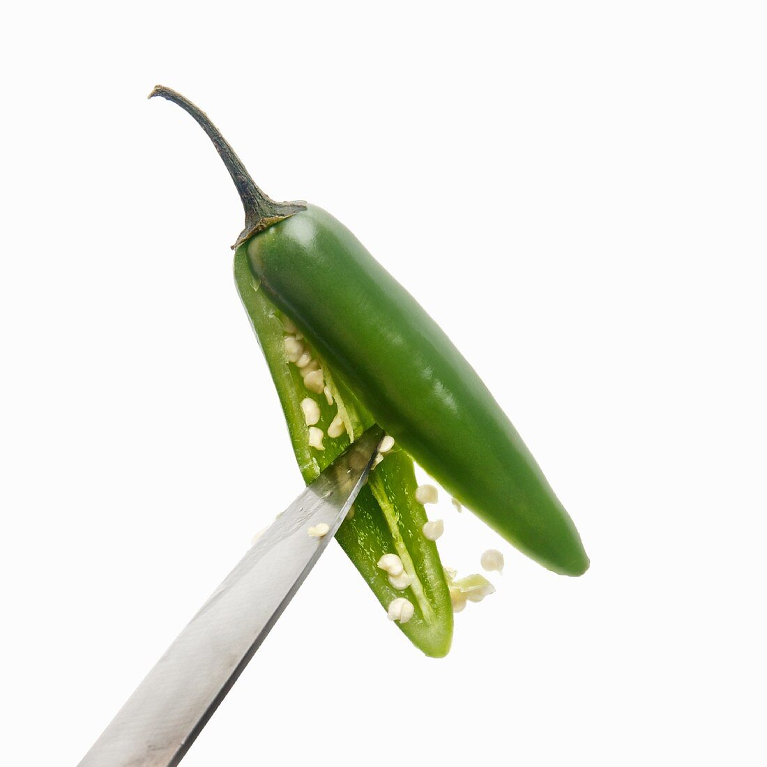 A green chilli pepper (chile serrano, sierra chilli) being deseeded