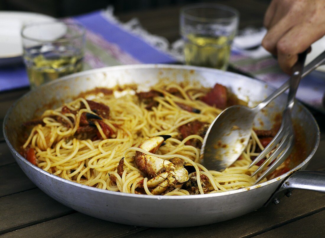 Spaghetti with tomatoes and crab in a pan