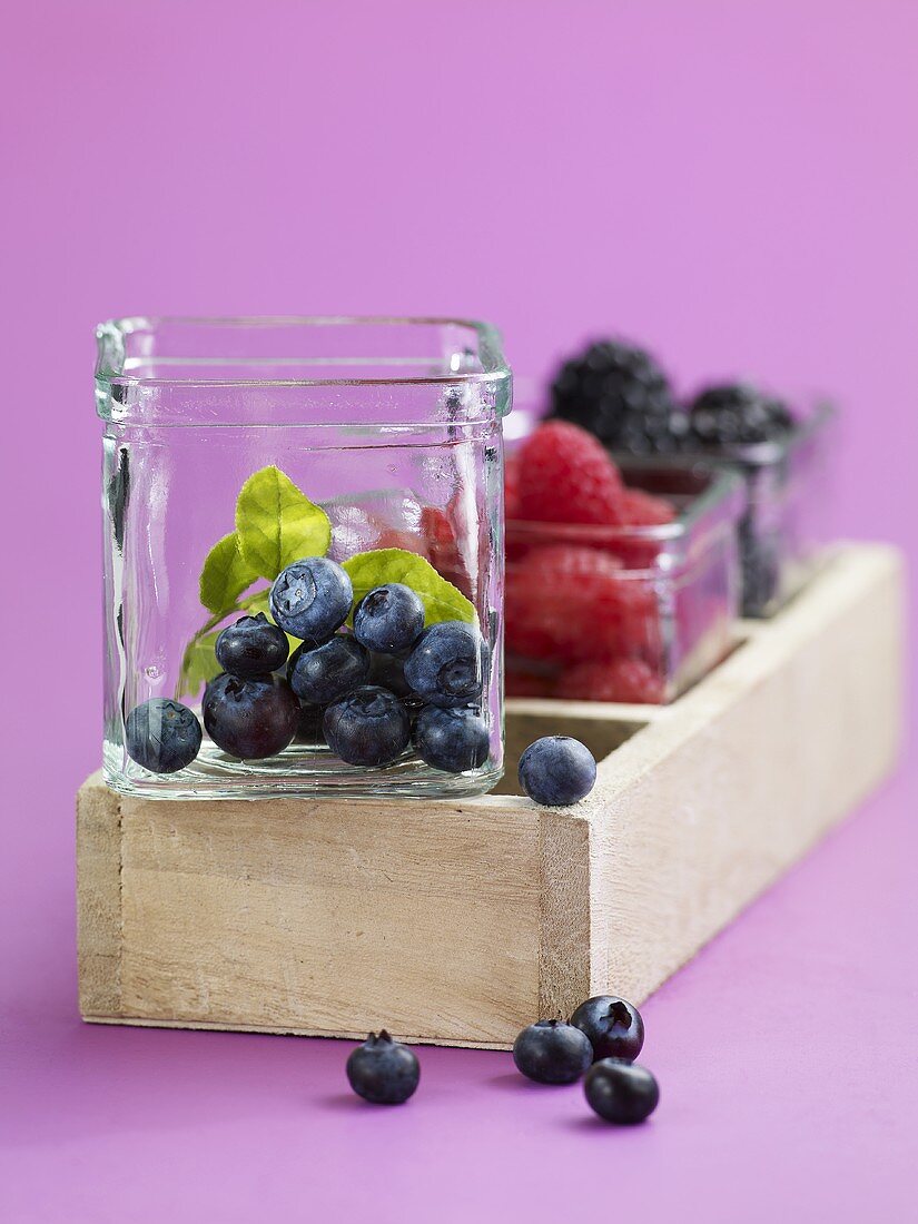 Blueberries, raspberries and blackberries in glass bowls