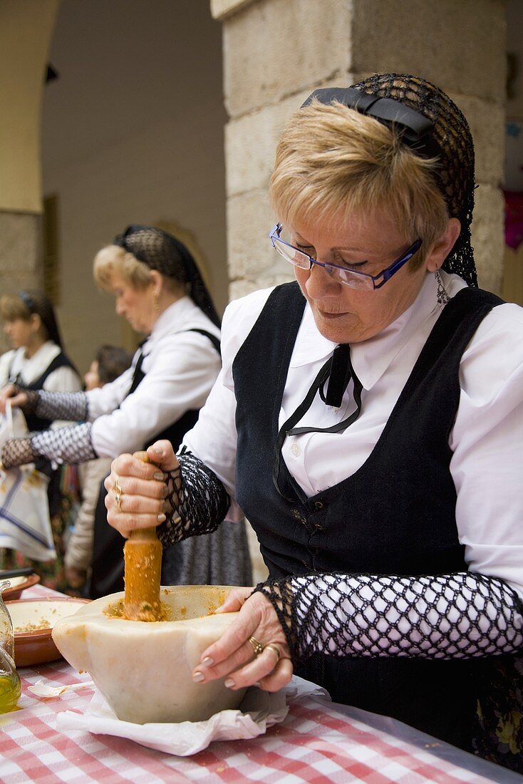 A woman in a traditional costume preparing sauce for calcotada (Spain)