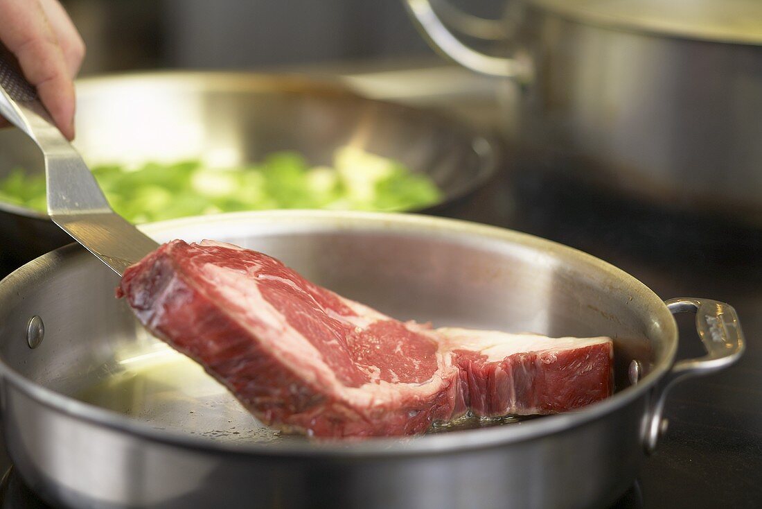 Beef steak being fried in a pan