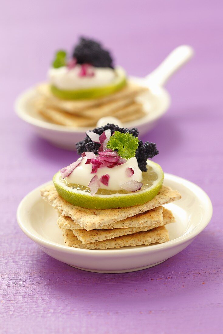 Crackers with sour cream, limes, onions and caviar