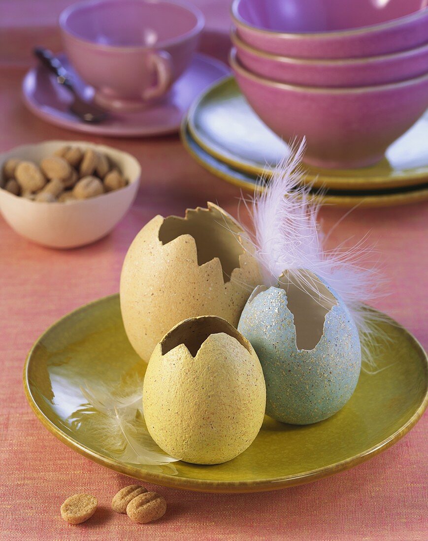 Drei farbige Eierschalen mit Feder als Osterdeko