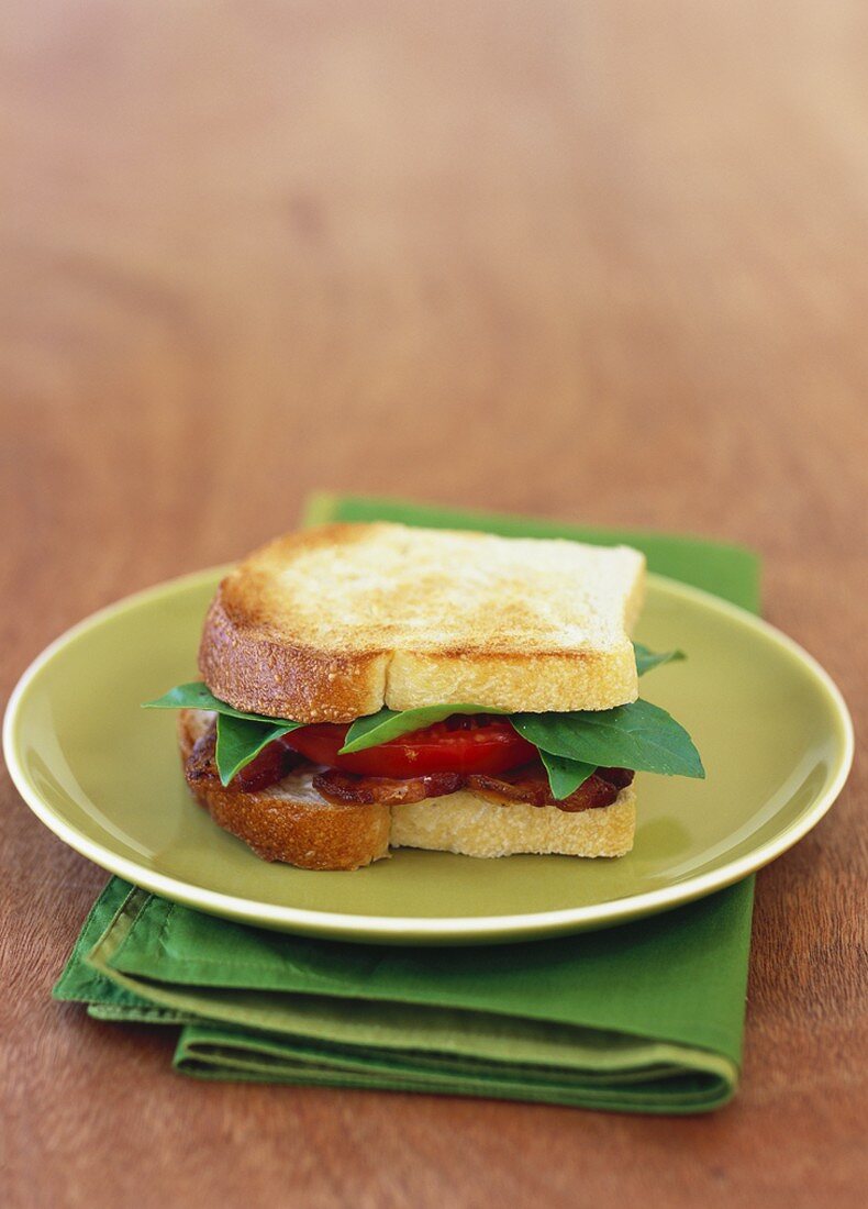 Fried bacon, tomato slices and basil in sandwich