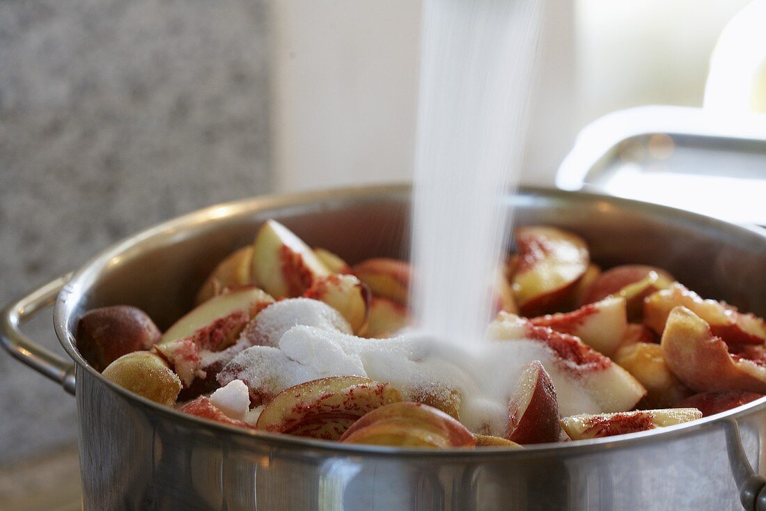 Pfirsichmarmelade zubereiten (Gelierzucker auf Pfirsiche im Kochtopf schütten)
