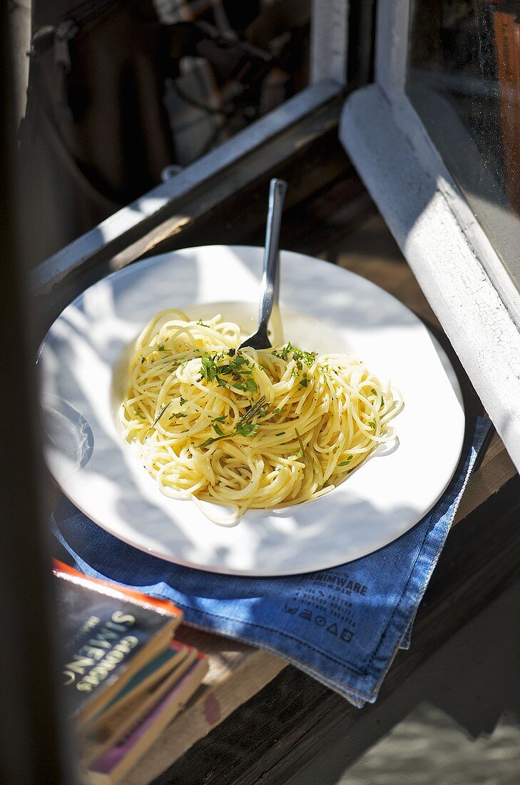 Spaghetti with herbs on plate by window