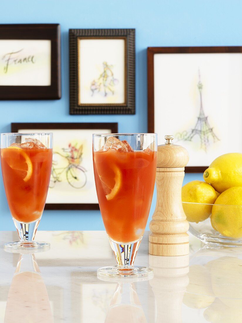 Orangencocktails, Pfeffermühle und Zitronen vor Bildern mit Motiven aus Paris