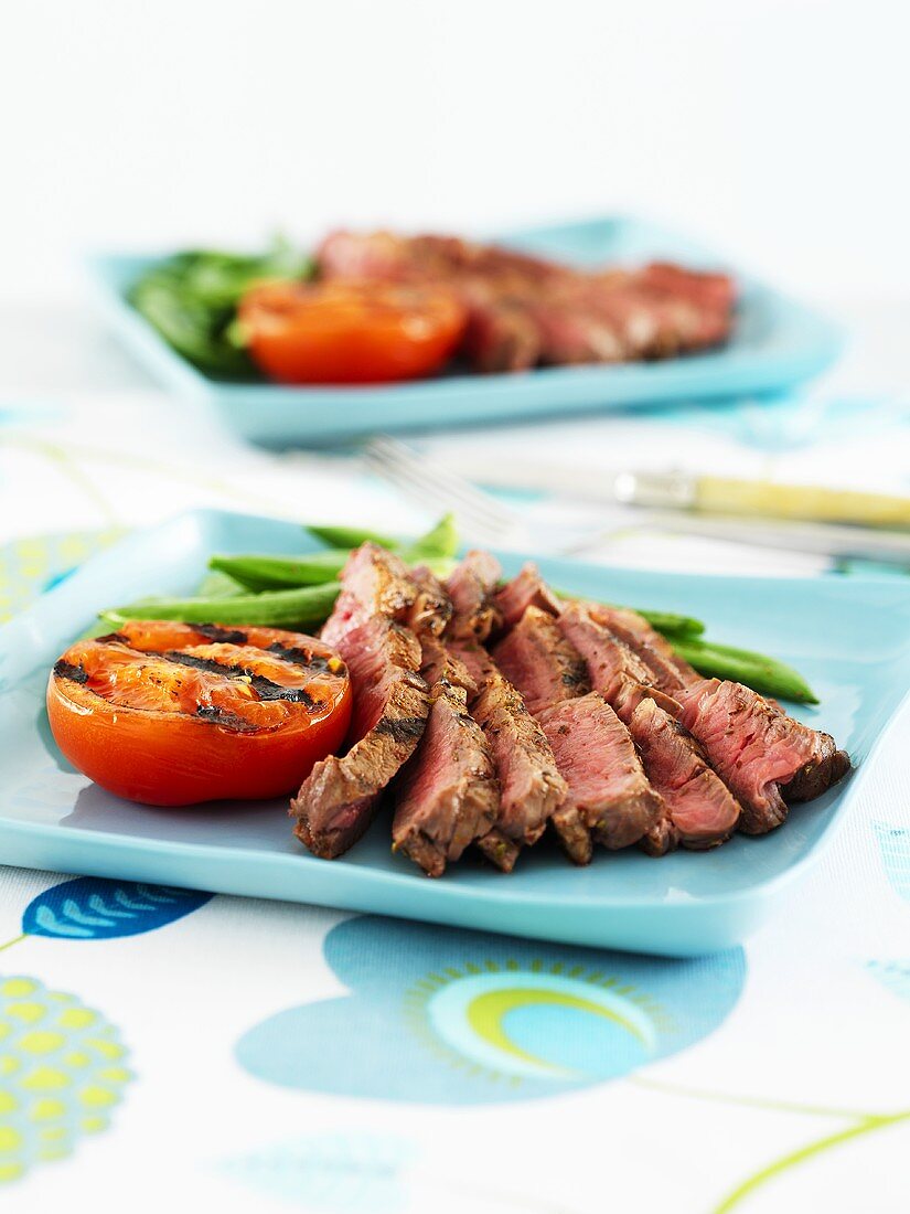 Sliced beefsteak with grilled tomato and green beans