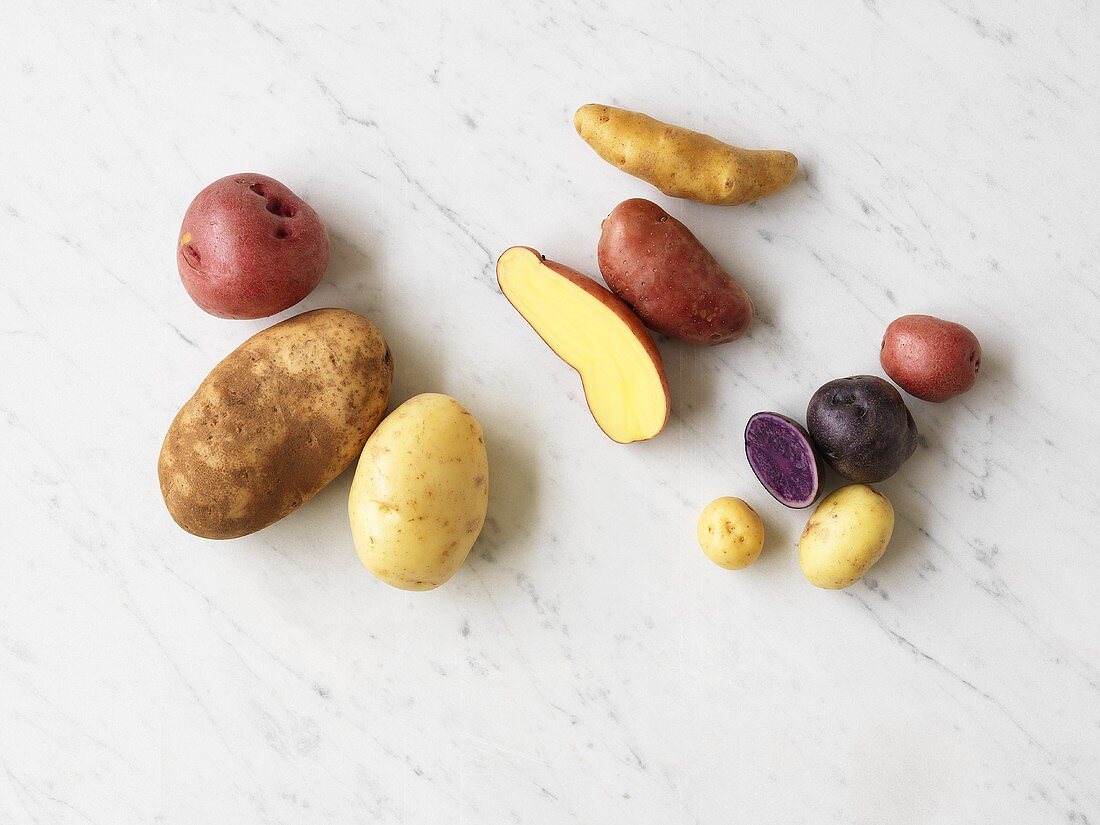 Various types of potatoes on marble background
