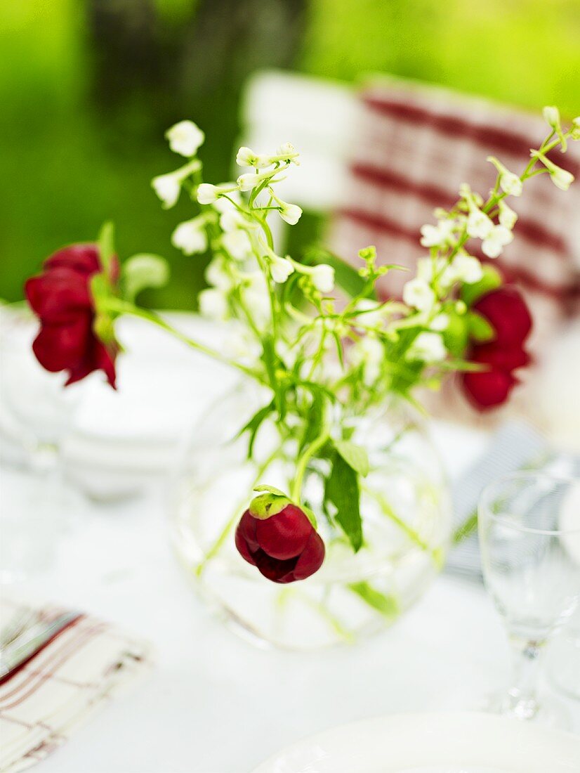 Vase of spring flowers on a table in a garden