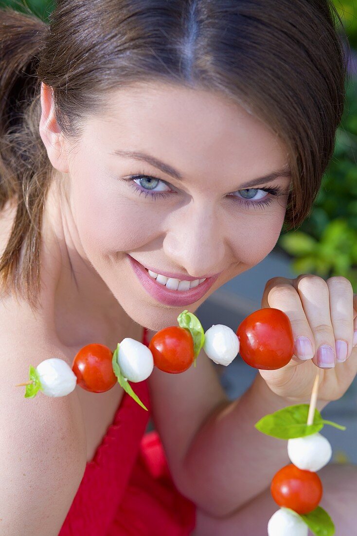 Junge Frau mit Tomaten-Mozzarella-Spiesschen