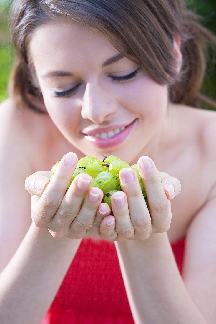 Young woman with her hands full of gooseberries