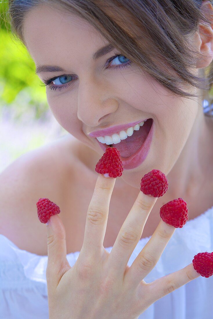 Young woman with raspberries on her fingers