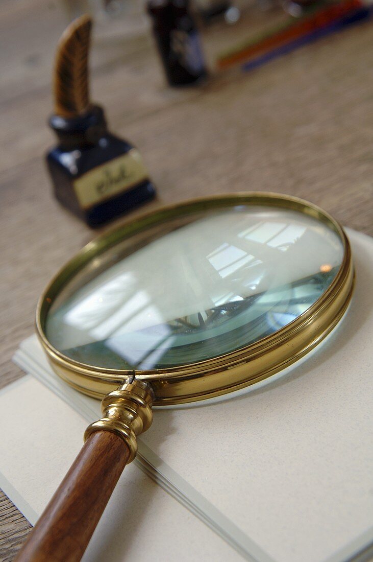 Magnifying glass, writing paper and bottle of ink