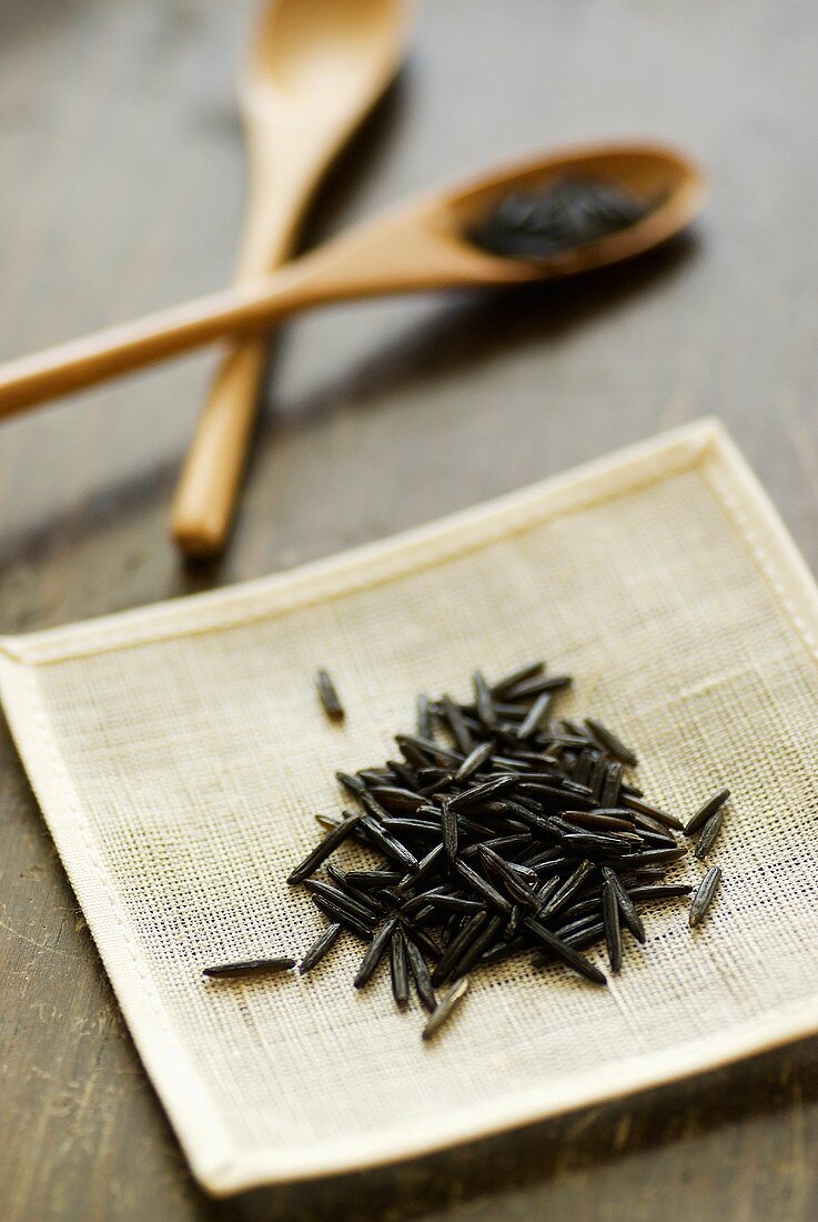 Wild rice on table mat, wooden spoons