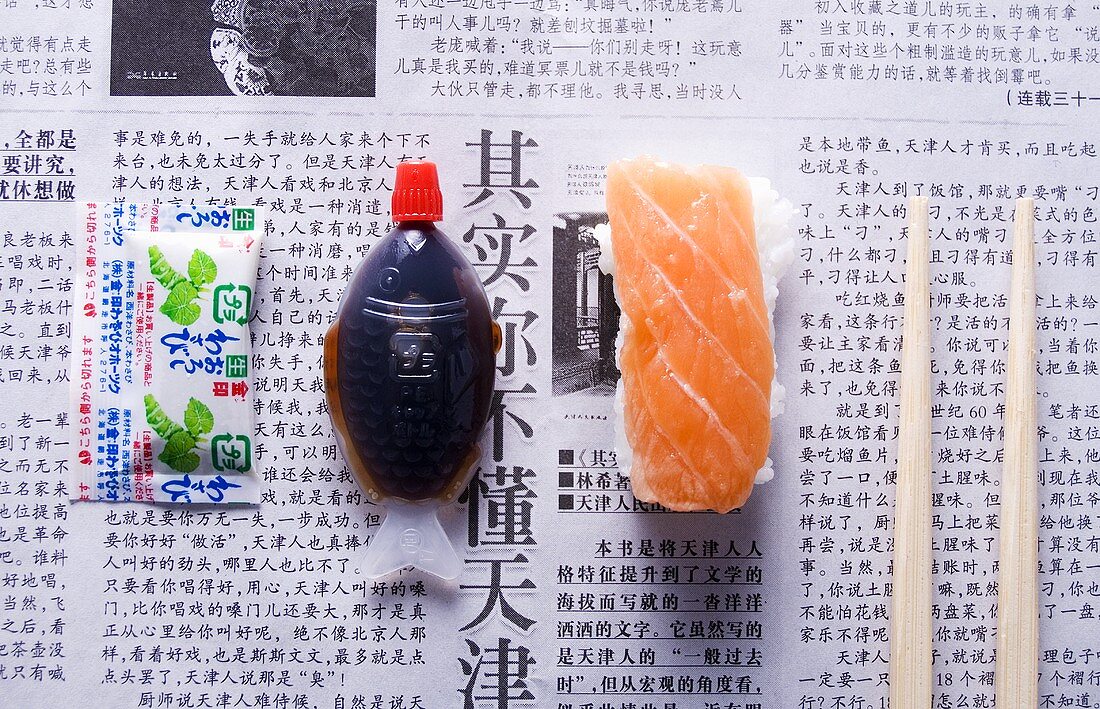 Nigiri-Sushi, Sojasauce, Wasabi und Essstäbchen auf Zeitung