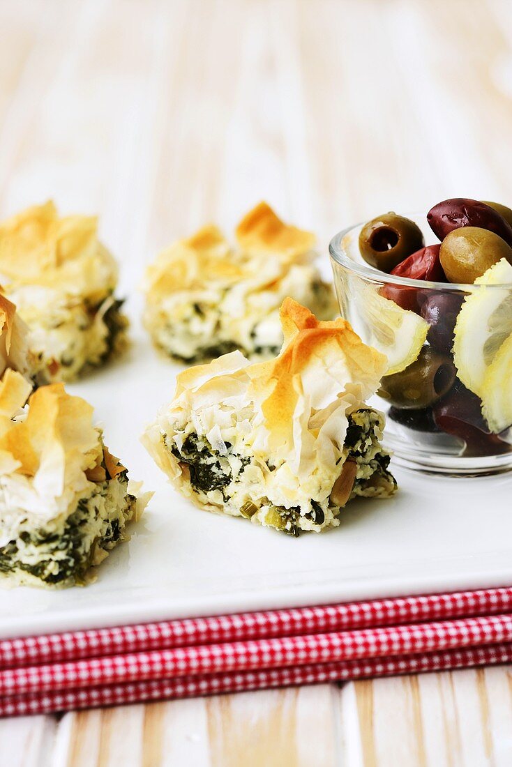 Pieces of spinach and feta pie with filo pastry, olives