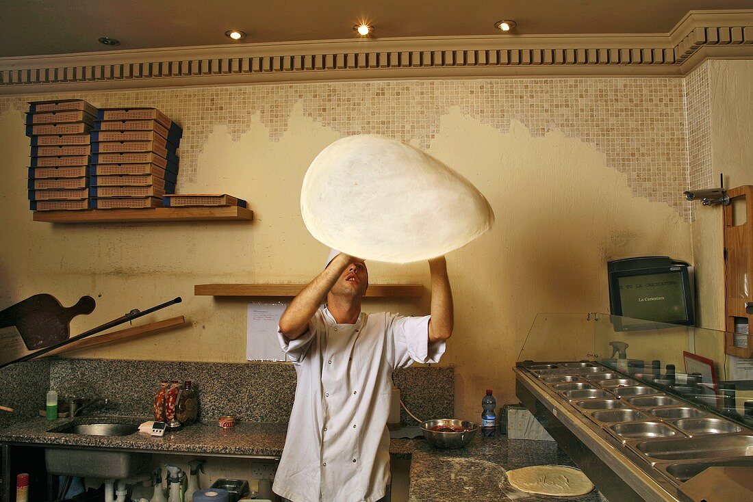 Italian pizza baker throwing dough into the air